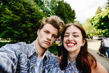 stylish happy hipster couple having fun laughing and taking selfies in the park in town in sunny spring time