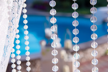 Decorations for the wedding ceremony by the pool with blue water. Wed decoration - candles, beads, butterfly, decorations, balloons, yarn.