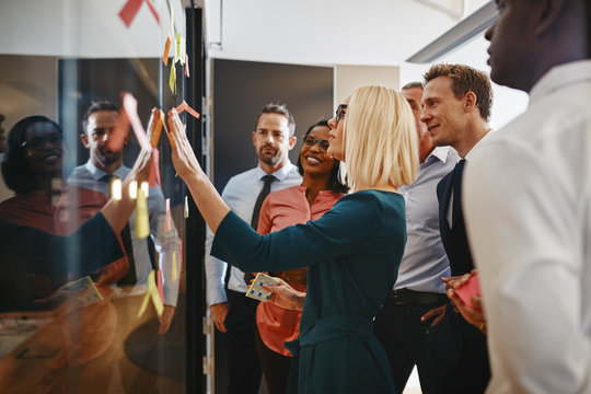 Young businesswoman and her team brainstorming with sticky notes - Powered by Adobe