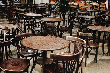 stylish wooden chairs and tables empty at rainy day on streets of europe city