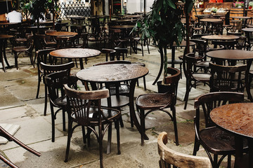 stylish wooden chairs and tables empty at rainy day on streets of europe city