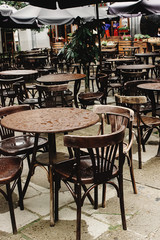 Fototapeta na wymiar stylish wooden chairs and tables empty at rainy day on streets of europe city