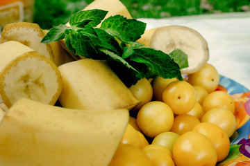 delicious bananas and cherry plums on colorful plate appetizer, yellow color, picnic outdoors, catering buffet at summer celebration