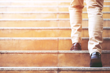Close up legs shoes of young business man One person walking stepping going up the stairs in modern...
