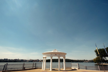 Obraz premium amazing view on white luxury stone arch on pier on background of sunny lake