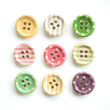 Wooden buttons with colorful stripes and colorful dots on a white background
