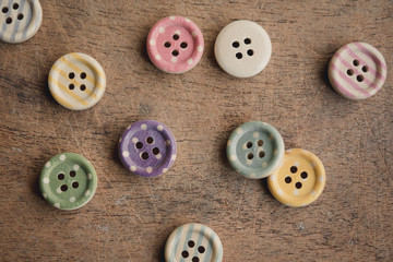 Wooden buttons with colorful stripes and colorful dots on a wooden background.