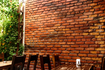 stylish wooden table and chairs on background of brick wall in restaurant, space for text