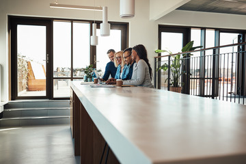 Businesspeople laughing while working on a laptop in an office