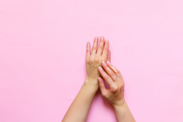 Woman's hands moisturizing cosmetic cream, lotion on a pink background with copy space, beauty, care concept. Pattern flat lay top view