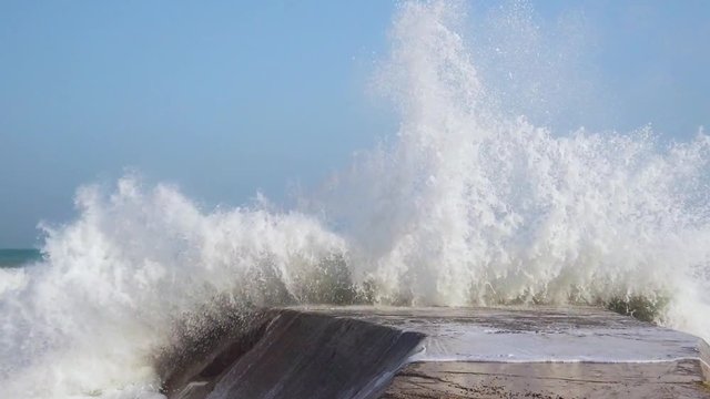Mare in tempesta con onde che si infrangono su un blocco di cemento. Rallentatore.