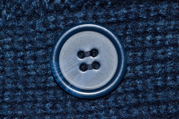 Navy blue macro swatch of a woolen garment with a blue button in the center of the image.