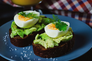 Healthy healthy snack (breakfast) - sandwich with avocado and egg on a gray plate.