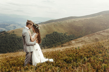 happy gorgeous bride and groom hugging in sun light, boho wedding couple, luxury ceremony at mountains with amazing view, space for text