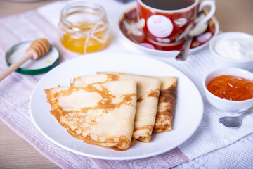 Traditional Russian pancakes with honey, sour cream and jam. Shrovetide. Maslenitsa week. Selective focus, close-up.