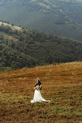 gorgeous bride posing on background of  sunny landscape,  boho wedding, luxury ceremony at mountains