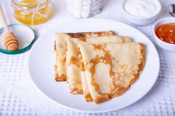Traditional Russian pancakes with honey, sour cream and jam. Shrovetide. Maslenitsa week. Selective focus, close-up.