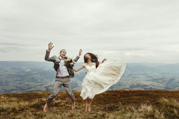 happy gorgeous bride and stylish groom jumping and having fun, boho wedding couple, luxury ceremony...