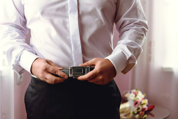 Obraz na płótnie Canvas stylish elegant groom getting dressed in the morning for a wedding