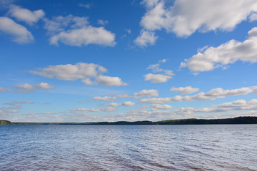 Obraz premium the thin line of the coast against the background of clouds and the blue sky