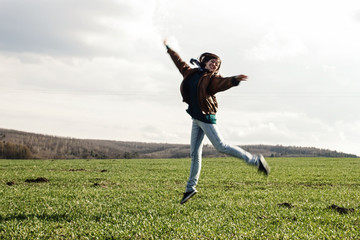 stylish beautiful brunette girl hipster jumpinh and having fun outdoors in spring field
