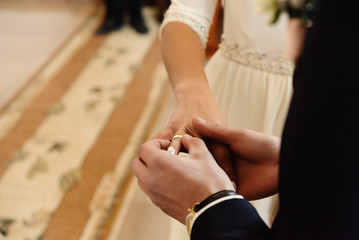 happy stylish bride and elegant groom exchanging wedding rings at ceremony at church