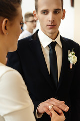 happy stylish bride and elegant groom exchanging wedding rings at ceremony at church