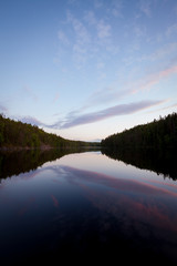 Calm forest lake at midsummer night sky reflection
