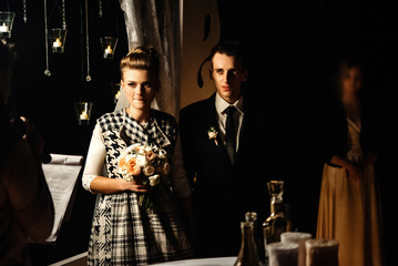 gorgeous bride and stylish groom at evening wedding ceremony walking down with candles, luxury  reception in restaurant