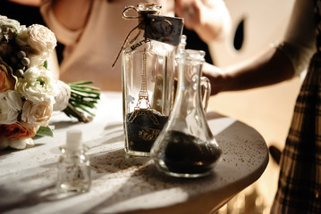bride and groom holding and pouring  glass jars with sand for wedding tradition ritual at evening reception