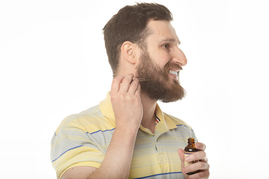 close up image of handsome man with pipette with beard oil.