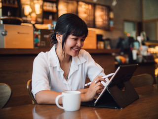 Asian woman drinking coffee in cafe and using laptop computer for working business online marketing