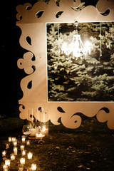 candle light in glass lanterns and wooden arch and lamp at luxury wedding ceremony in evening, decor and arrangements
