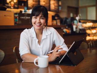Obraz na płótnie Canvas Asian woman drinking coffee in cafe and using laptop computer for working business online marketing