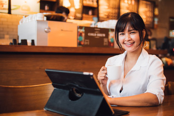 Fototapeta premium Asian woman drinking coffee in cafe and using laptop computer for working business online marketing