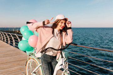 Laughing girl in pink cap coming to sea after bike trip to enjoy beautiful view in morning....