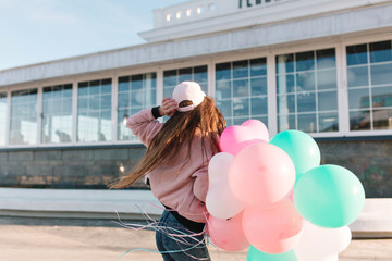 Slim stylish girl in pink cap dancing outside in morning while wind playing with her long dark...