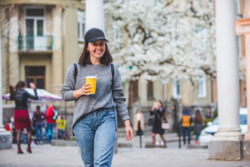 young stylish woman walking by street with coffee cup