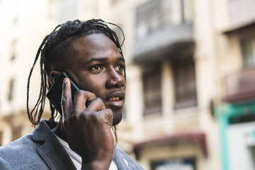 Attractive African American Guy portrait talking on mobile phone on the street