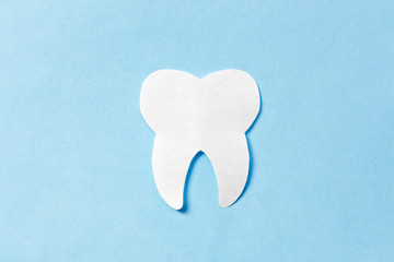Clean tooth on blue background. Concept healthy teeth or destruction enamel, decay, caries.