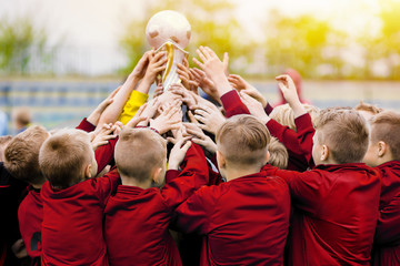 Children's soccer team raising golden football trophy