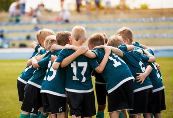 Kids football team building team spirit. Soccer children team in huddle. Group of boys united...