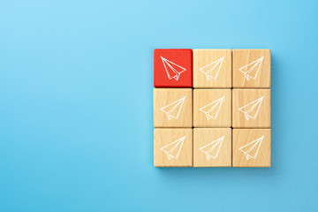 Red wooden blocks with paper plane icons that are different from the group, blue background, Business concept for new ideas creativity and innovative solution.