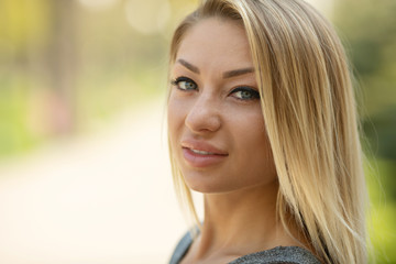 Naklejka premium Beautiful smiling girl outdoor. A portrait of a beautiful blonde young Caucasian woman outdoor. 