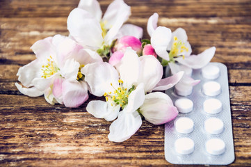 pills and flowers on wooden background