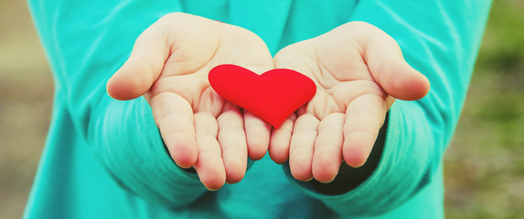 The heart is in the hands of the child. Selective focus.