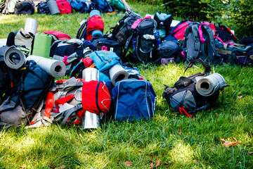 Colorful backpacs on the grass waiting for departure of trek. Hiking, adventure, group vacation concept.