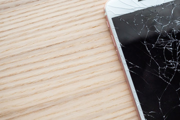 broken glass of mobile phone screen on wooden background