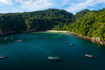 Fototapeta na wymiar Aerial drone view of traditional longtail fishing boats in a bay on a small, tropical island (Cavern Island, Mergui, Myanmar)