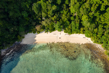 Aerial drone view of a small beach on a lush, green tropical island (Cavern Island)